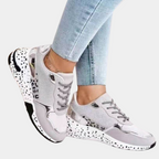 Dames sneakers in goud en beige met glinsterende details, zwarte en witte zool, en veters. Modieuze sportschoenen voor casual en sportieve outfits.