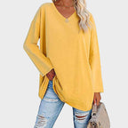 Dame i hot pink genser, V-hals, lange ermer, kombinert med lyseblå distressed jeans. Perfekt for trendy, casual stil.